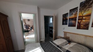 Un dormitorio con una cama, un armario de madera y vista a la habitación contigua.