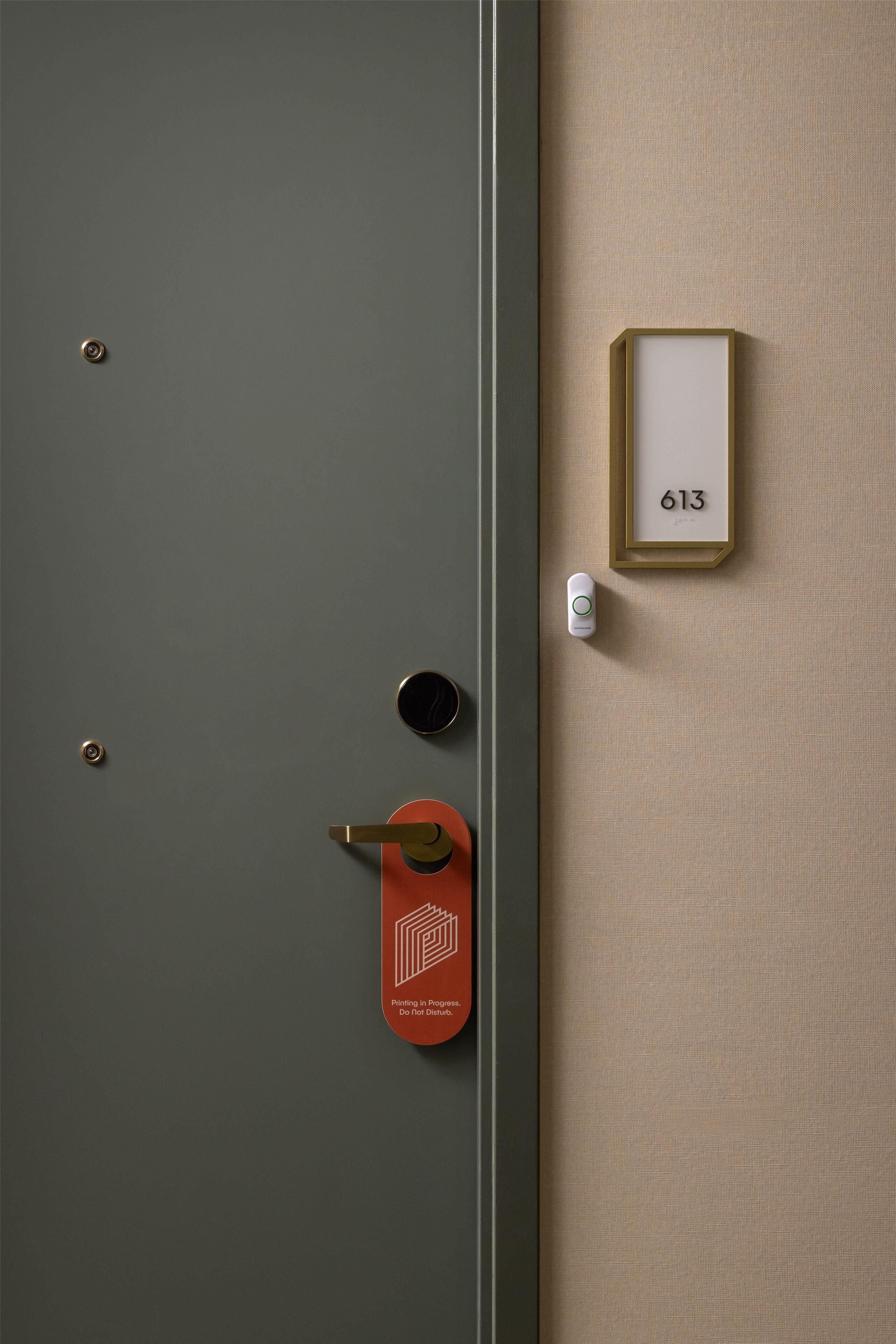 Une porte avec un trou de serrure, un interphone et une plaque indiquant le numéro de la pièce.