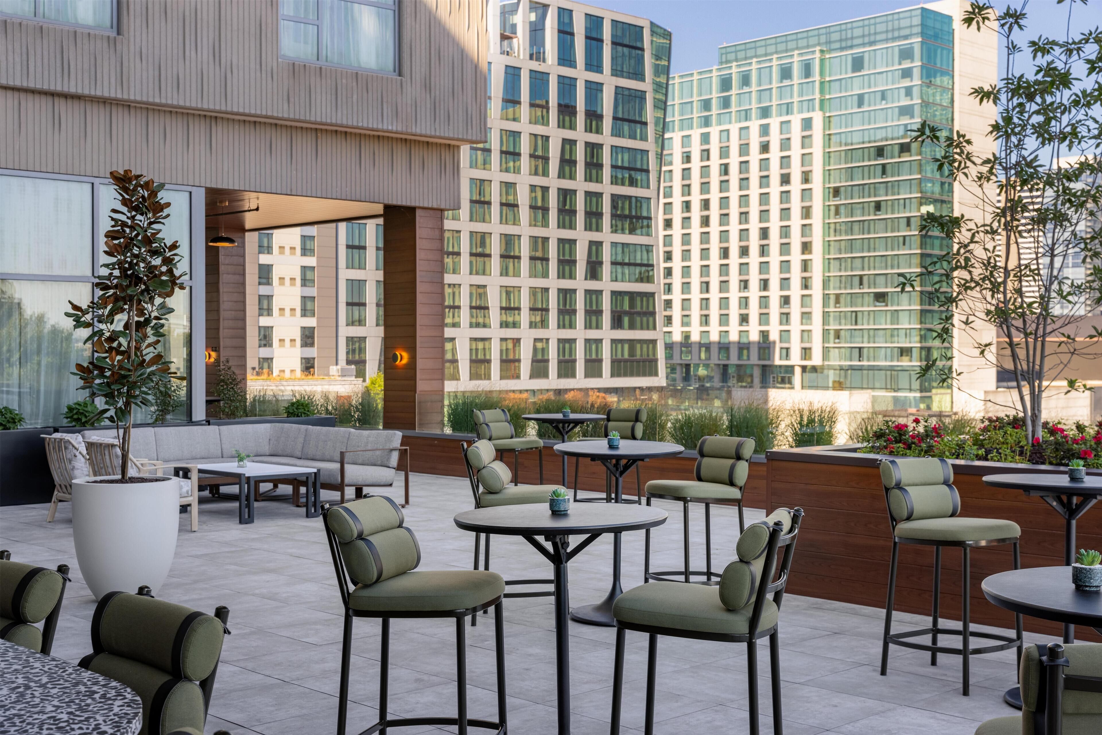 An outdoor patio area with seating and tables, surrounded by modern buildings.