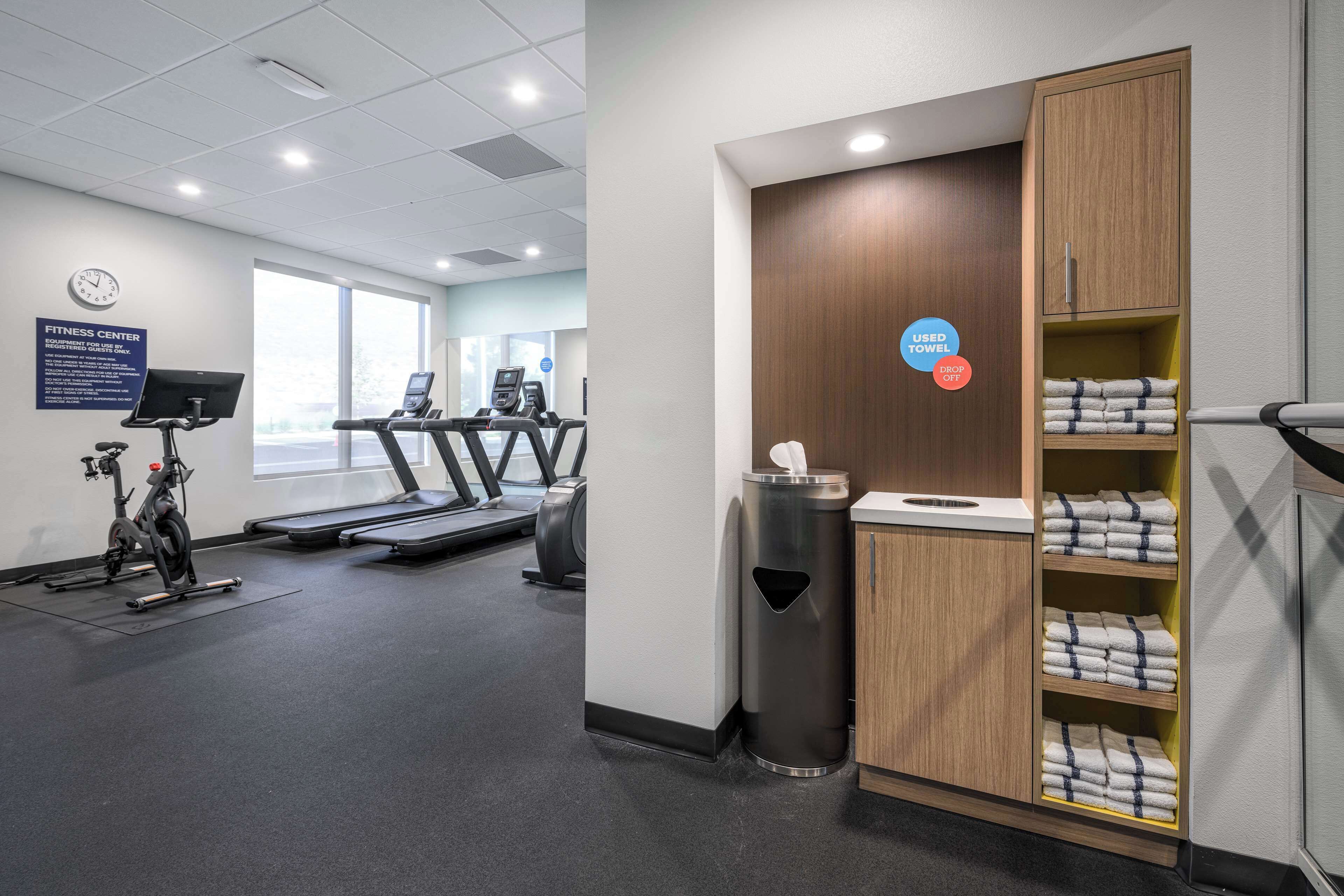 A fitness center with treadmills, an elliptical, and a wall clock.