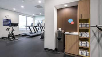 A fitness center with treadmills, an elliptical, and a wall clock.