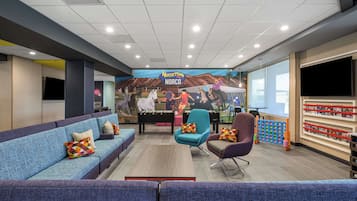 A spacious lobby with a blue sofa, teal armchairs, and a colorful mural depicting a horse race.