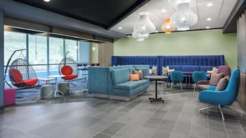 Un moderno espacio de sala de estar con arreglos de asientos, incluyendo sofás y sillones, y un amplio ventanal que proporciona luz natural.