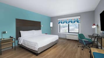 Habitación de hotel moderna con una cama grande, un escritorio, una silla y ventana con vistas.