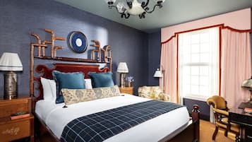 A bedroom with a large bed, wooden headboard, two nightstands, a desk, and a chair.