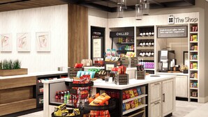 Interior de una cafetería moderna con un mostrador central, secciones de bebidas refrigeradas y una variedad de aperitivos y bebidas en exhibición.