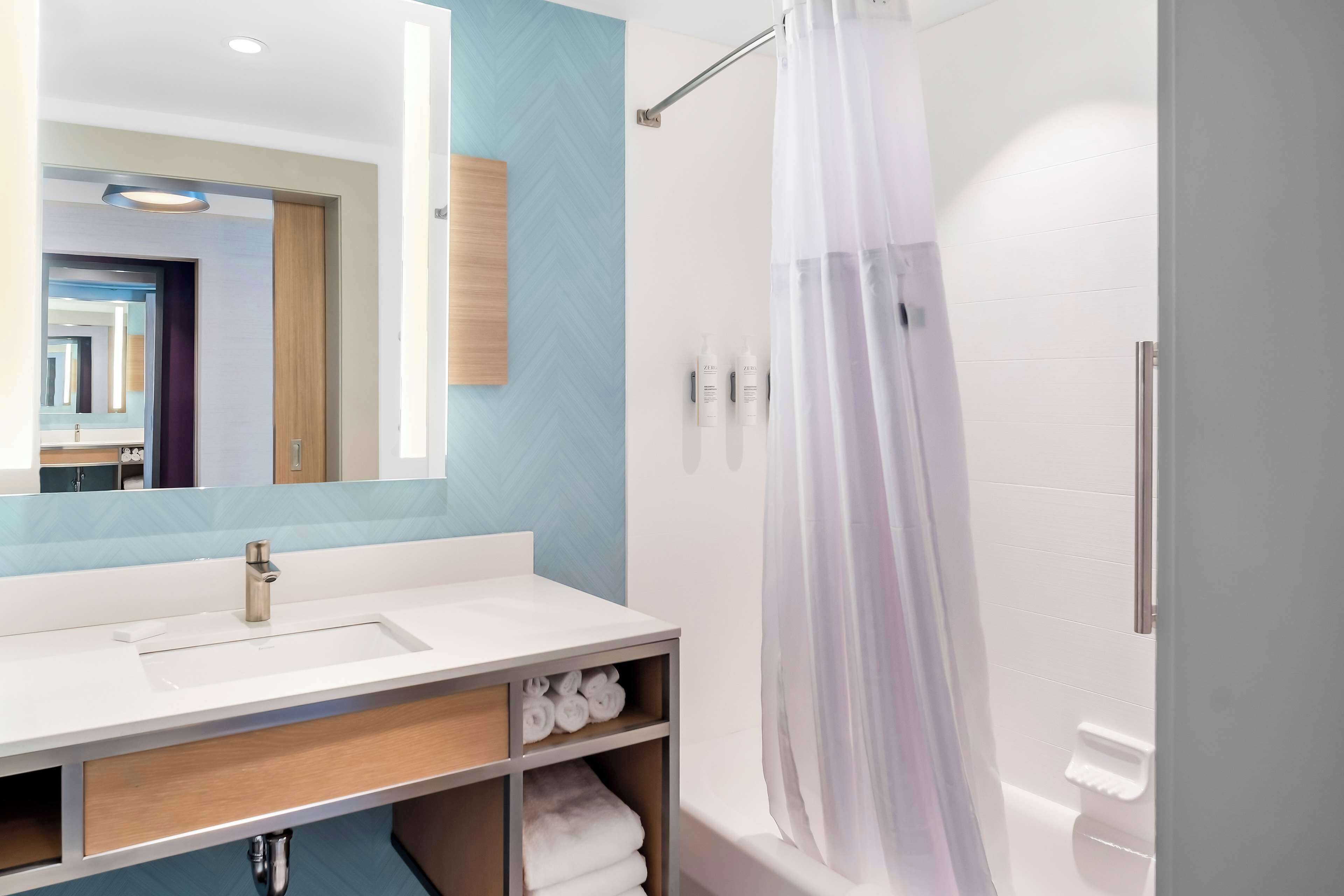 Ein modernes Badezimmer mit Waschbecken, Spiegel und Duschvorhang.