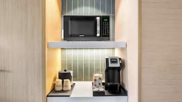 Eine Küchenzeile mit Mikrowelle, Kaffeemaschine und Kaffeetassen.