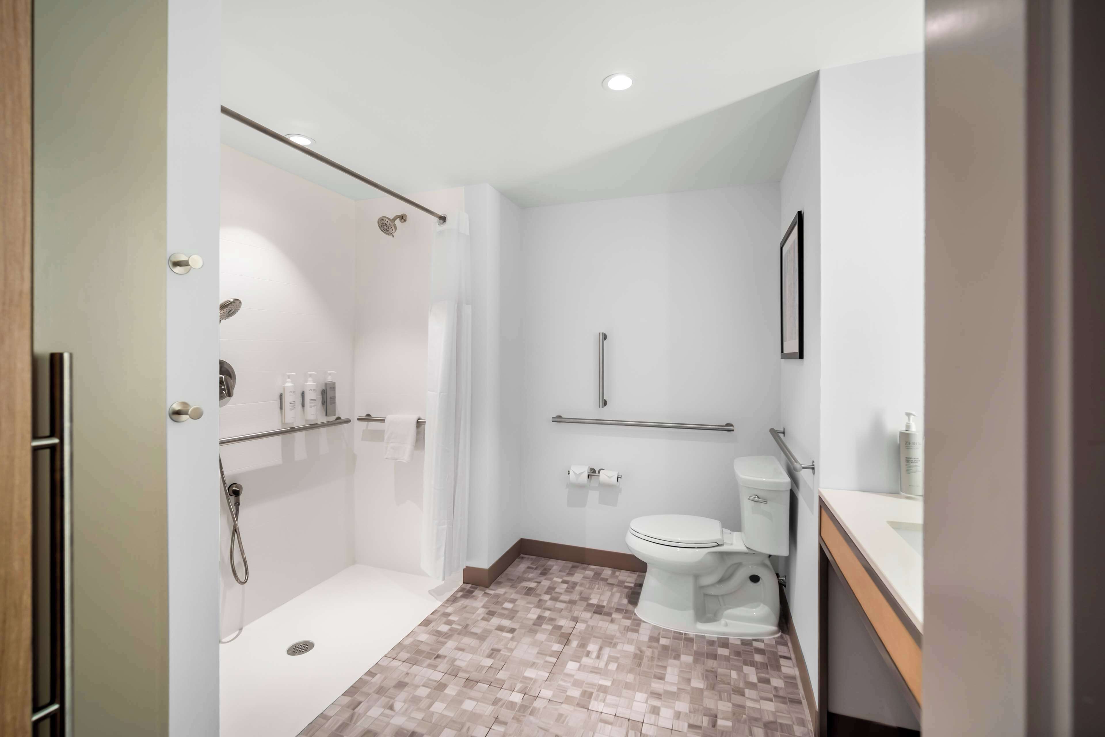 A modern bathroom with a shower, toilet, and sink.