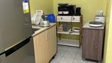Eine kleine Küche mit Kühlschrank, Mikrowelle und einer Arbeitsplatte.