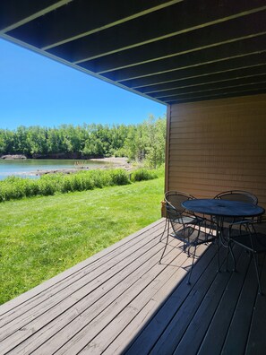 A wooden deck with a table and chairs, overlooking a river and forested area. - Lake Superior Retreat Near Two Harbors; Waterfront Views + Access; Cozy getaway! (Two Harbors)