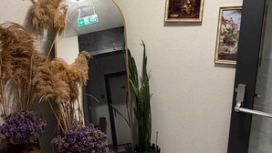 Un pasillo con un espejo, plantas en macetas, una puerta y una cámara de seguridad instalada en la pared.