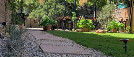 A paved pathway leading to a grassy area with potted plants and outdoor furniture.