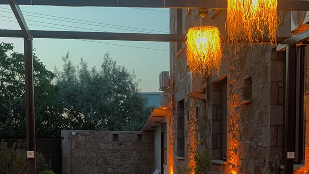 Un patio al aire libre con suelo de piedra, mobiliario de madera y pared de piedra.