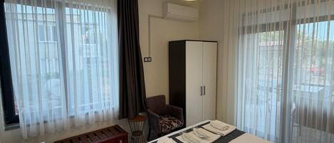 A hotel room with a bed, a desk, a chair, a bench, and a wardrobe.