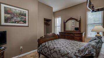 A bedroom with a bed, dresser, mirror, and a painting on the wall.