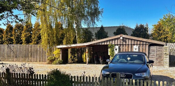 Ein Gebäude mit Garage, ein Auto davor und einem Holzzaun.