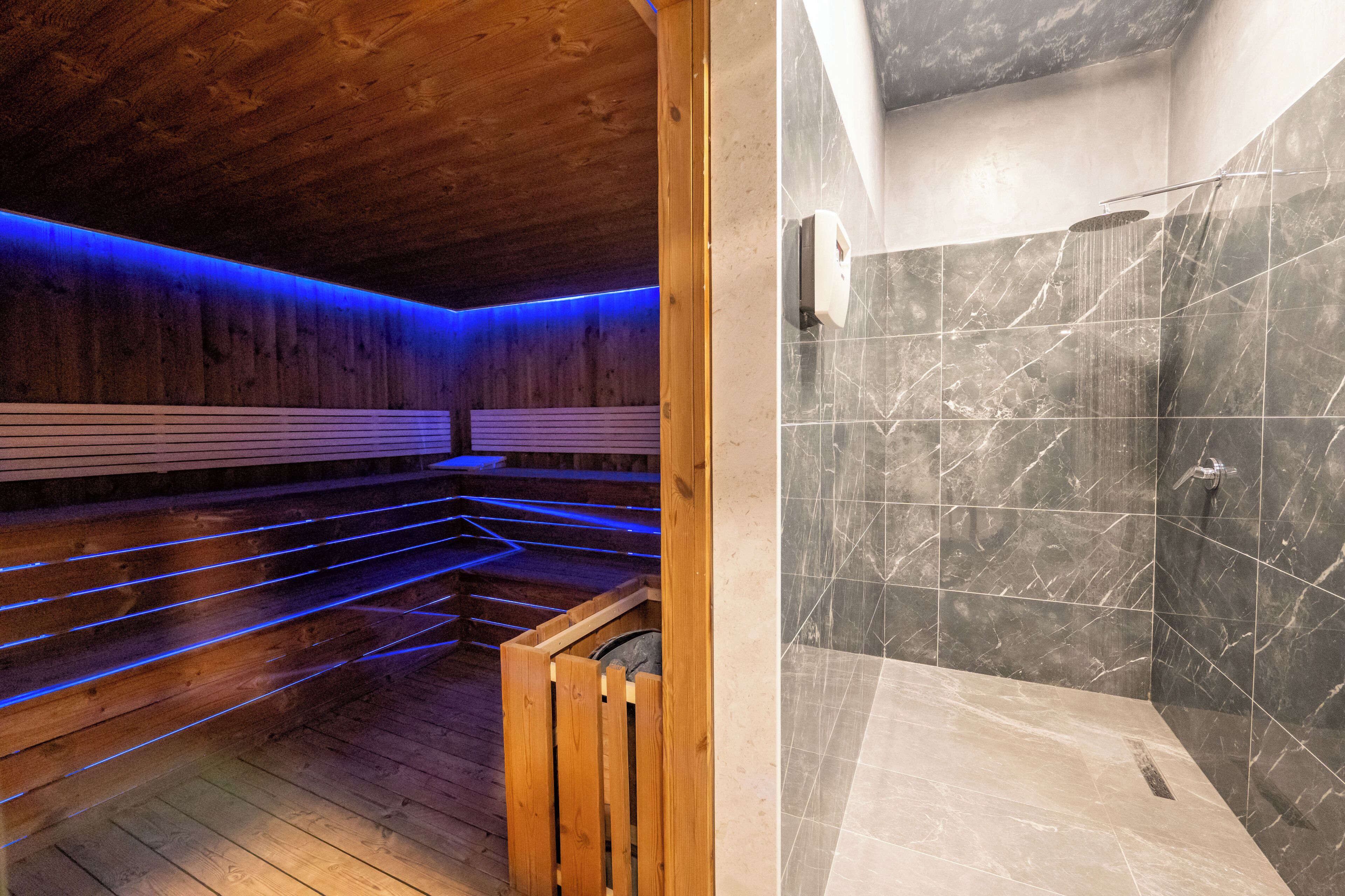 Una sauna con bancos de madera y un área de ducha separada con azulejos de mármol.
