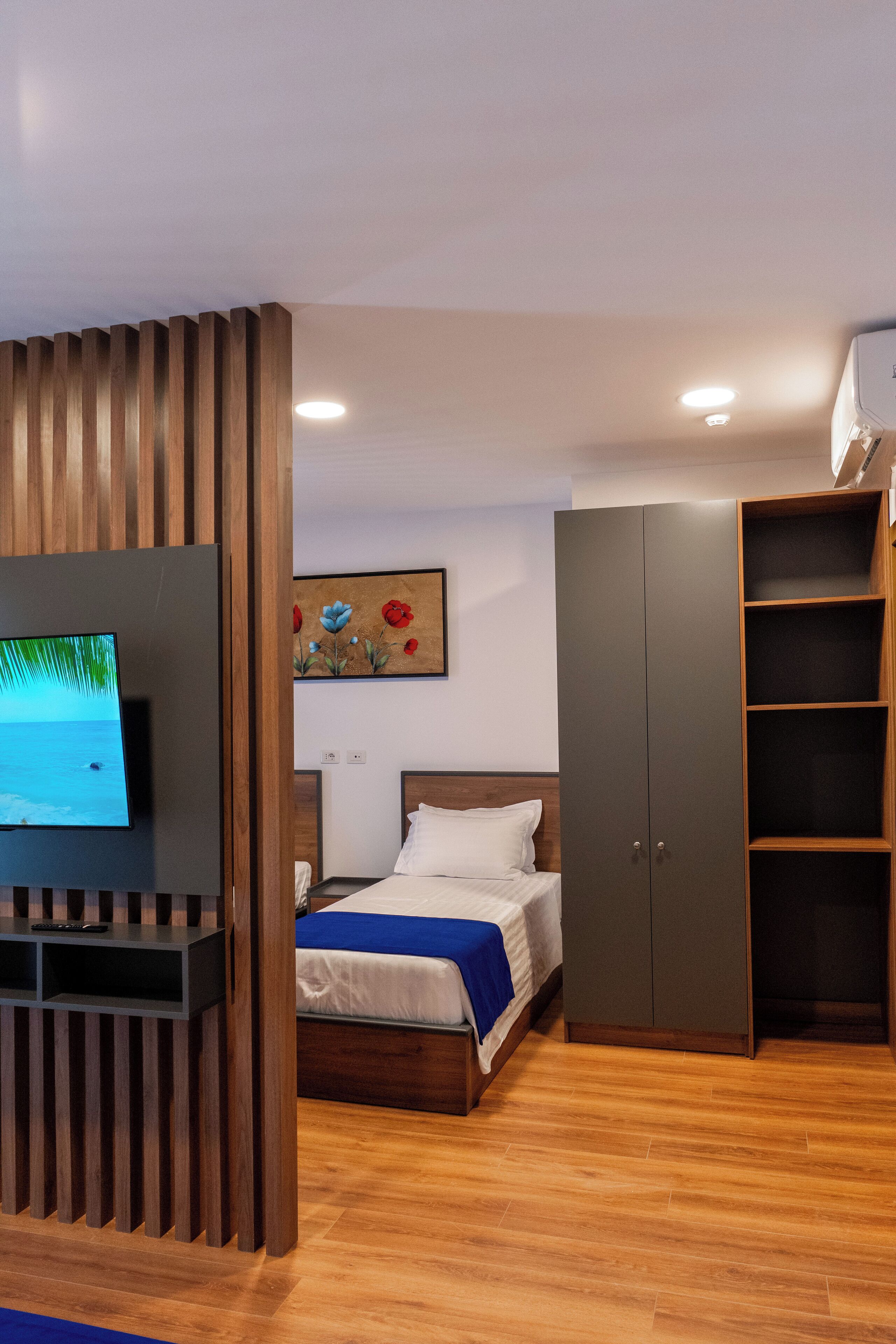 Ein Schlafzimmer mit Bett, Fernseher, Kleiderschrank und einem Bild an der Wand.