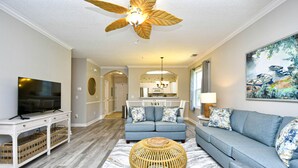 A modern living room with a television, sofa, and a ceiling fan.