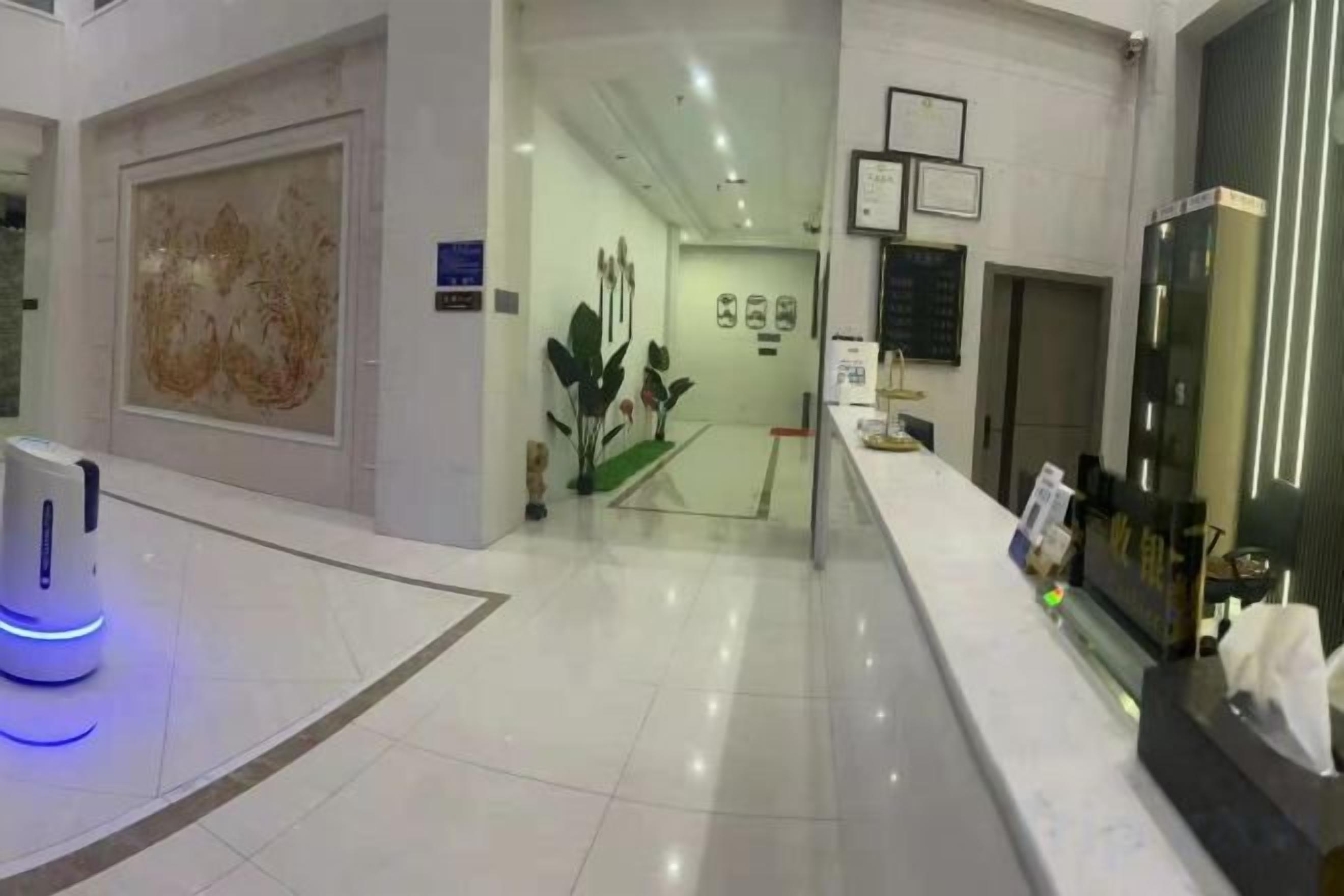 A hotel lobby with a reception desk, a large abstract painting, and a glass display case.