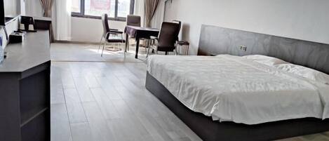 A modern hotel room with a large bed, a desk, and a chair.