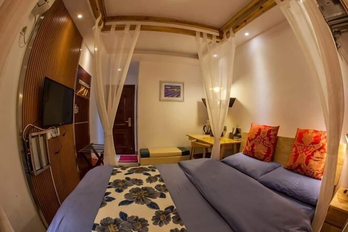 A bedroom with a bed, a TV, a desk, and a chair.