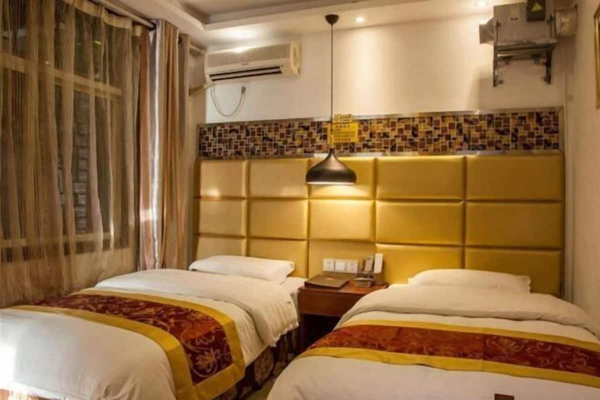 A hotel room with two beds, a headboard with a mosaic tile design, an air conditioning unit, and a hanging lamp.