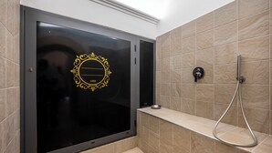 Un baño con una puerta negra, ducha y azulejos color beige.
