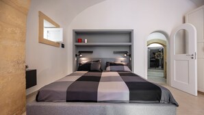 Un dormitorio moderno con una cama, estantes empotrados y una puerta que da a otra habitación.