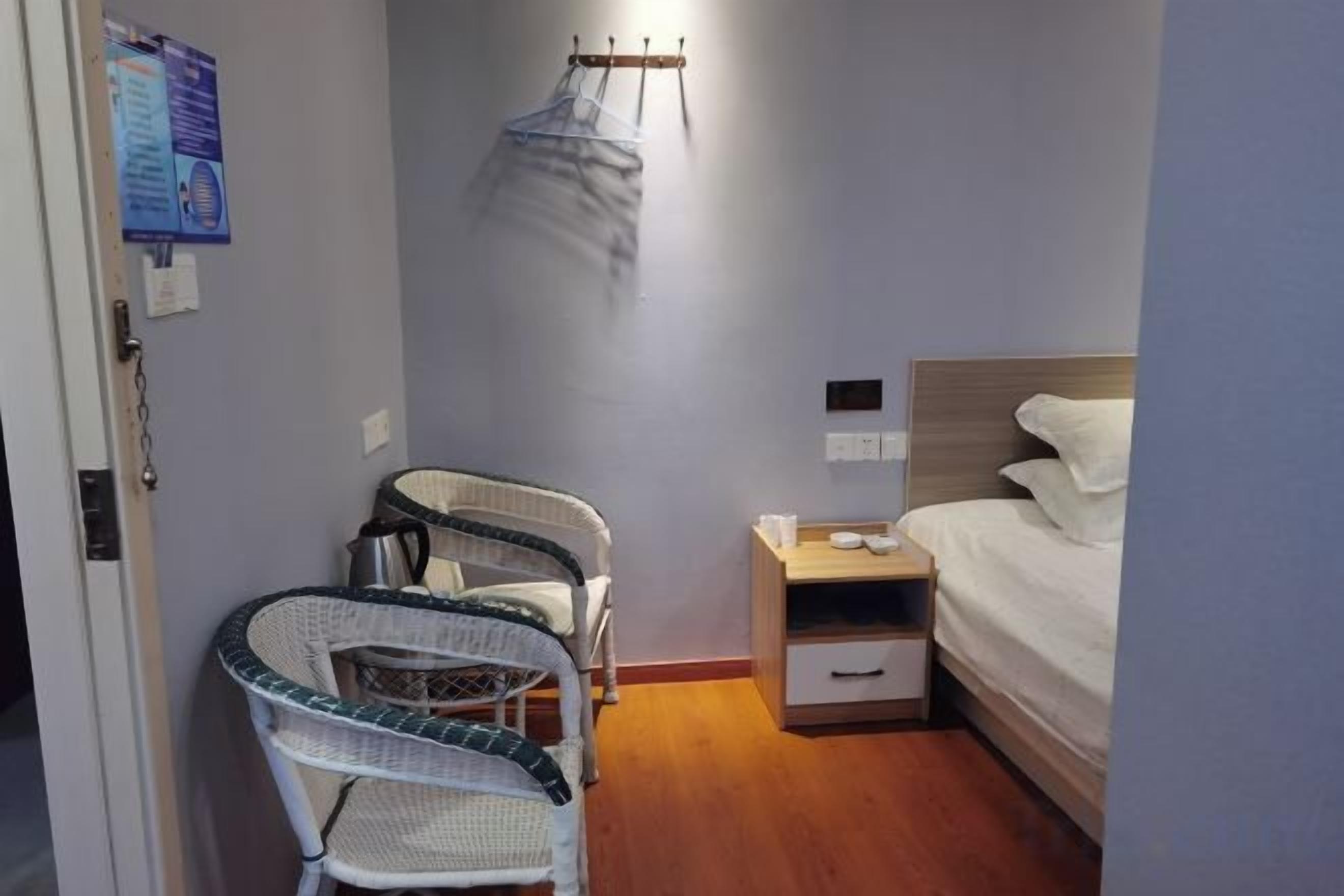 A hotel room with a bed, a nightstand, a chair, and a hanging mosquito net.