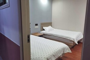 A room with two single beds, wooden headboards, and a small wooden nightstand between them. - Chengrong Hotel (Shanghai)