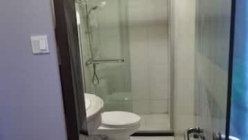 Uma casa de banho com sanita, cabine de duche com vidro e porta de vidro.