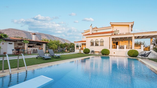 A swimming pool with lounge chairs, a patio area, and a mountain in the background. - Renko Royal Villa  Luxury villa in Athens Riviera. Private Pool,  garden & BBQ (Lagonisi)
