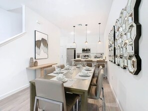 Enjoy meals in this stylish dining area with a long table and pendant lights.