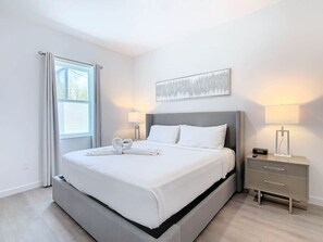 Relax in a serene space with a large bed, bedside tables, and a beautiful artwork above.