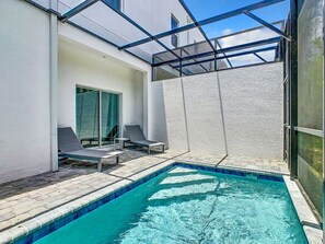 Relax by the pool surrounded by a glass enclosure and lounge chairs.