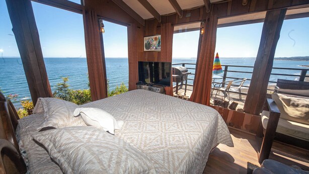 Une chambre avec un grand lit, une télévision et une vue sur la mer.