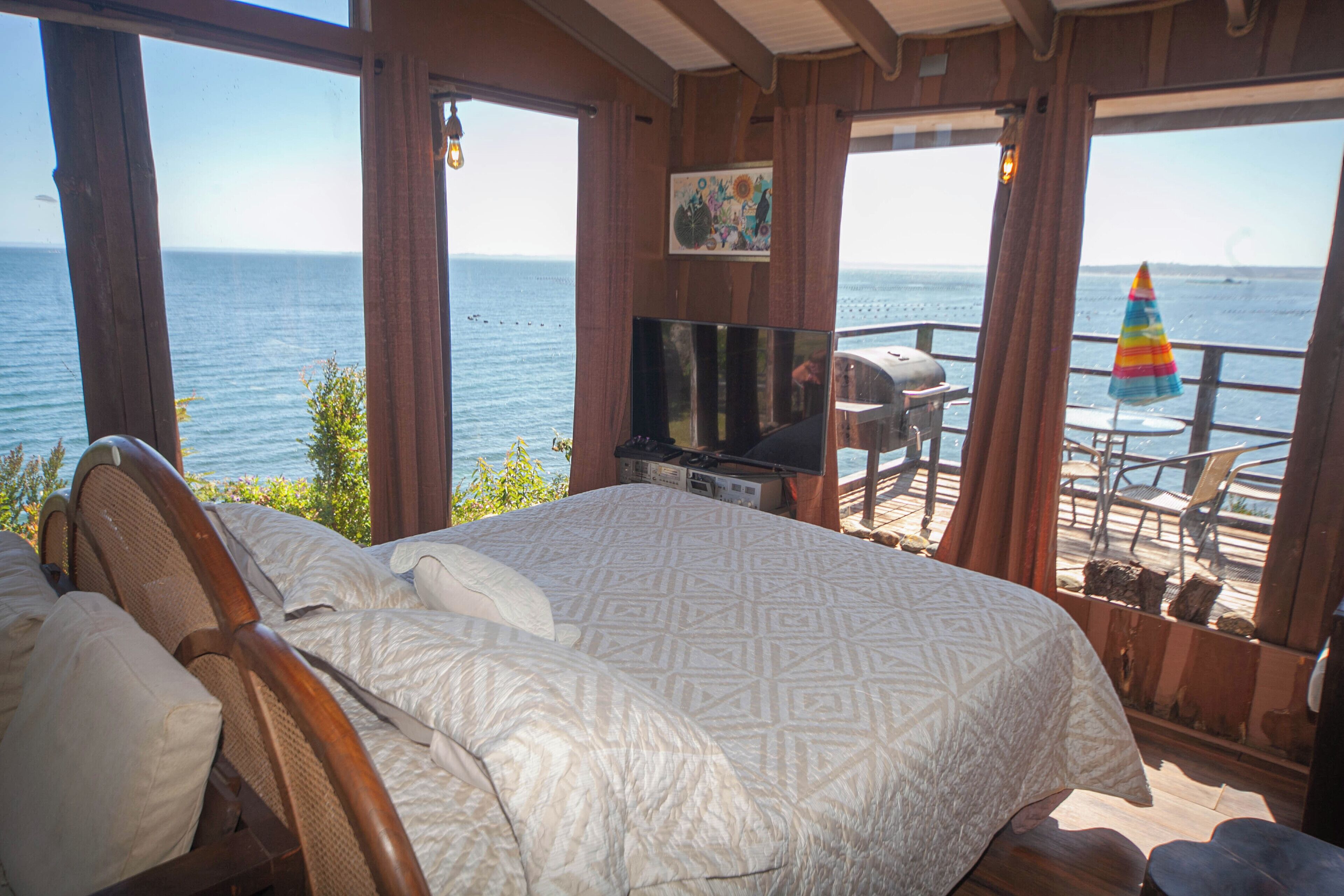Un dormitorio con una cama grande, televisión y vista al mar.