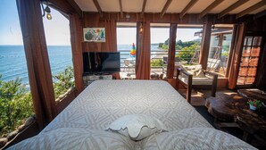 Une chambre dotée d’un grand lit, d’une télévision et d’un balcon offrant une vue sur la mer.