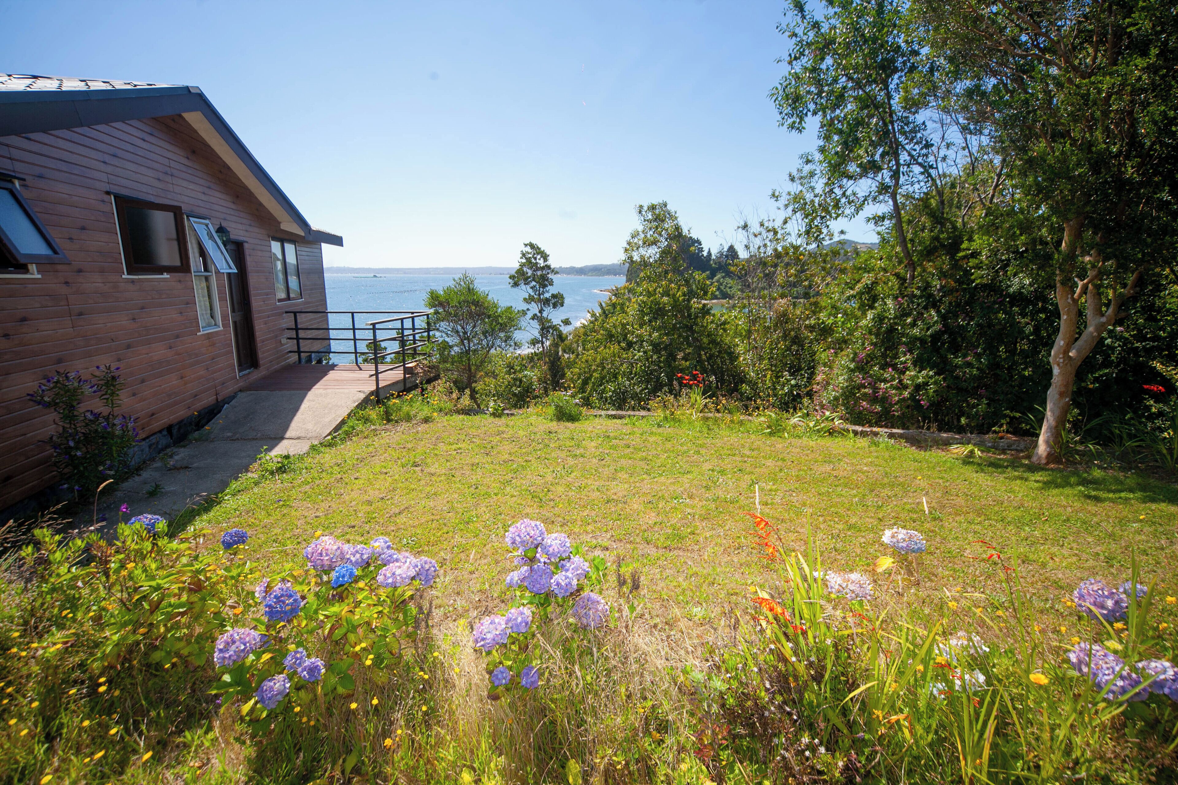 Une maison moderne avec une façade en bois, un balcon et une vue sur la mer.