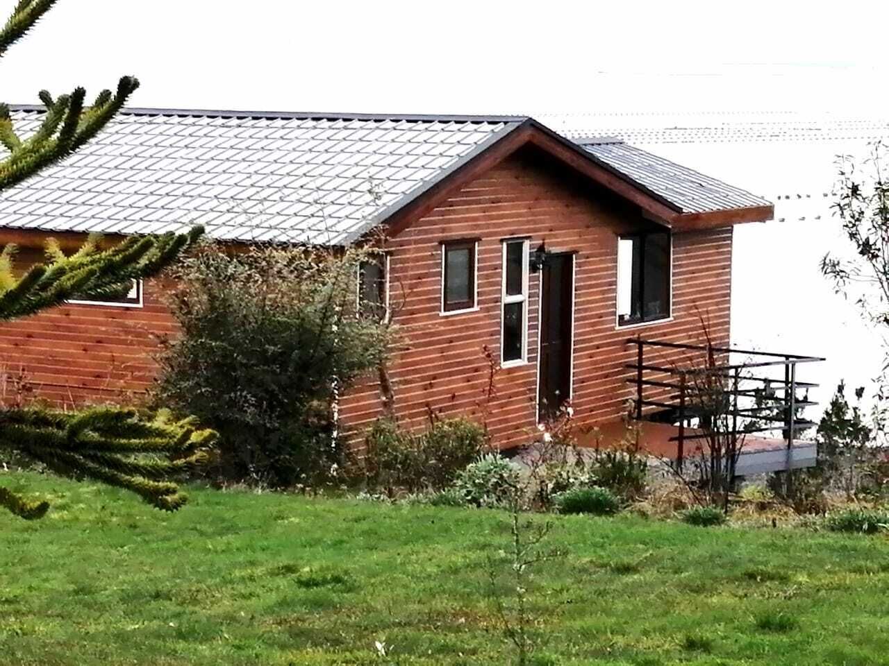 Una casa de madera con techo de tejas, una puerta principal y un pequeño porche.
