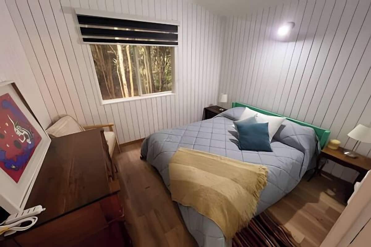 Una camera da letto con un letto, una finestra, una scrivania e una sedia.