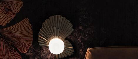 Una lampada moderna con una particolare lampada a forma di ventaglio, posata su un muro strutturato.