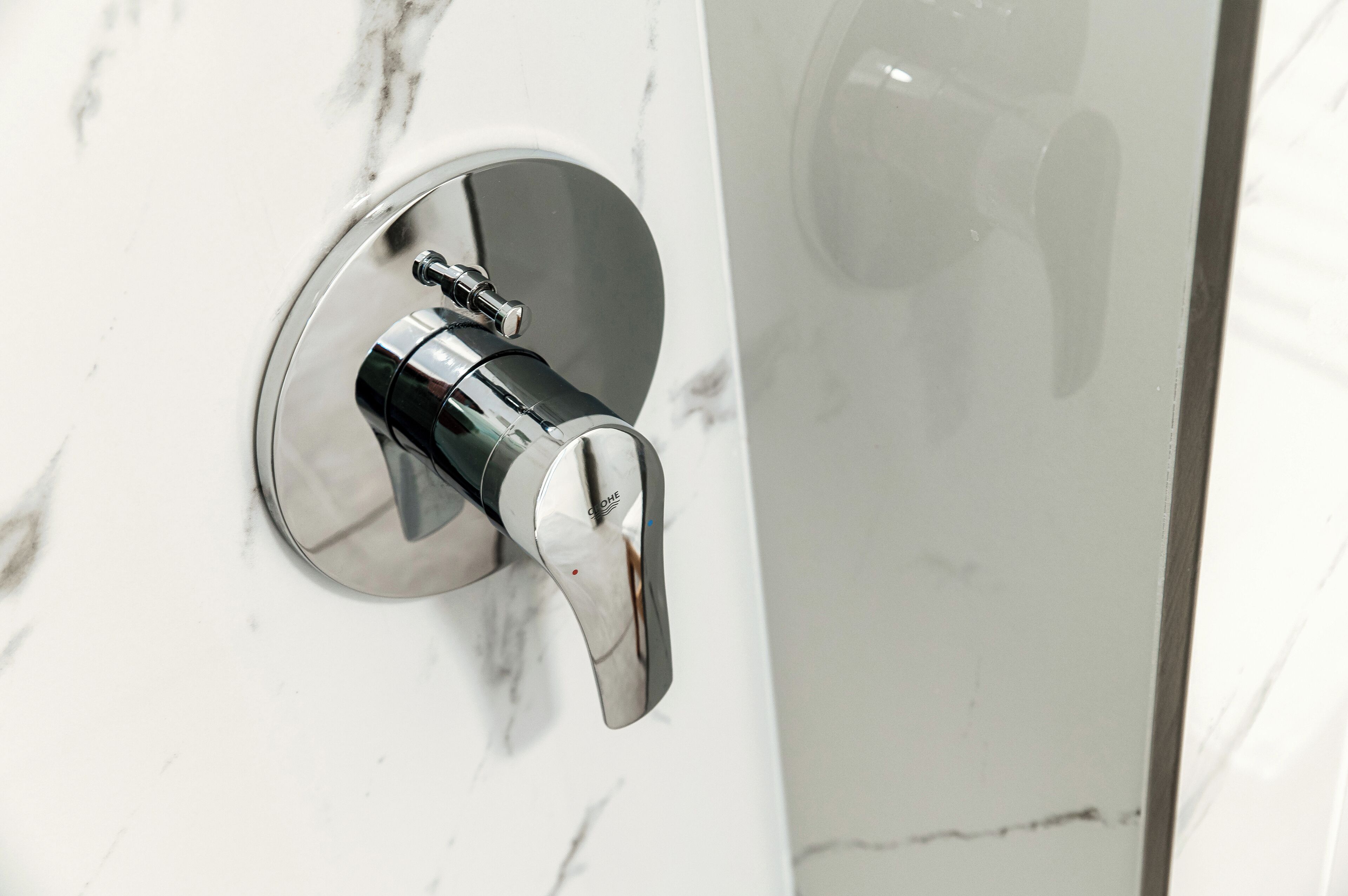A modern bathroom with a sleek, chrome faucet mounted on a white marble wall.