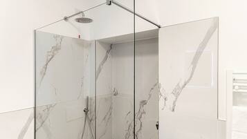 Un box de ducha moderno con azulejos de mármol y puerta de cristal.