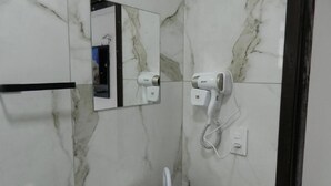 A bathroom with marble walls, a mirror, and two hair dryers mounted on the wall. - Estalagem Floradas da Serra  (São Joaquim)