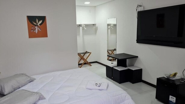 A bedroom with a bed, a desk, a mirror, and a television. - Estalagem Floradas da Serra  (São Joaquim)
