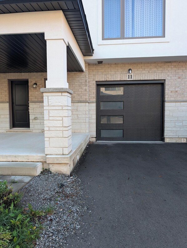 A modern two-story house with a garage, a front door, and a small porch area.