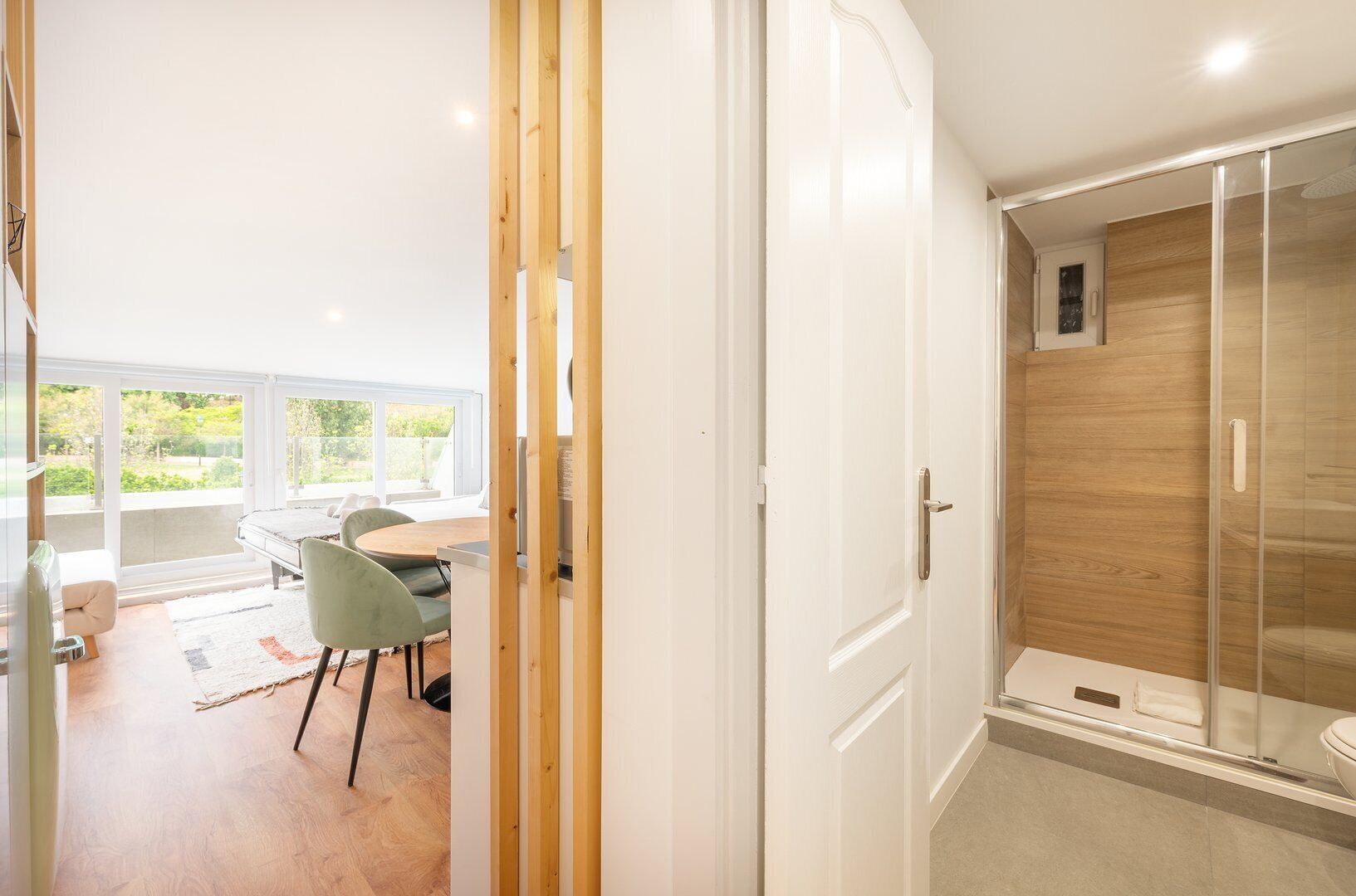 Een moderne badkamer met een douchecabine van glas, een houten wastafelmeubel en een wit toilet.